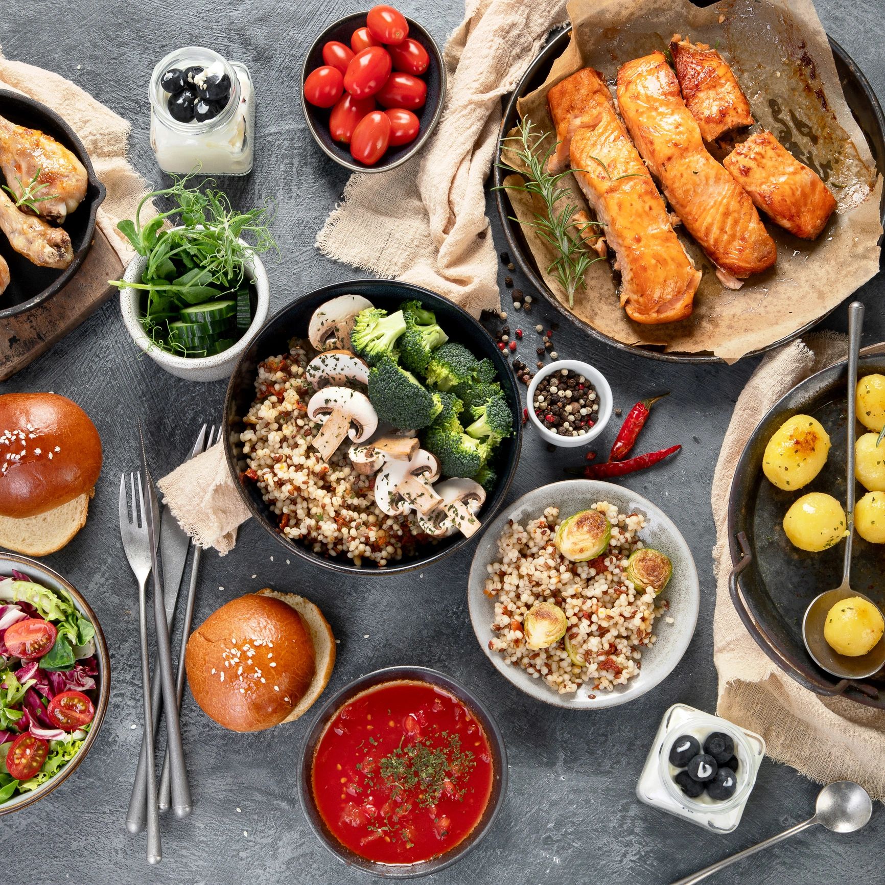 A healthy meal spread with salmon, vegetables, soup, and fresh salad.