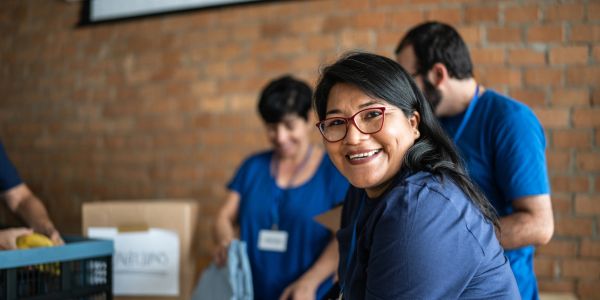 Smiling woman in glasses volunteering with others.