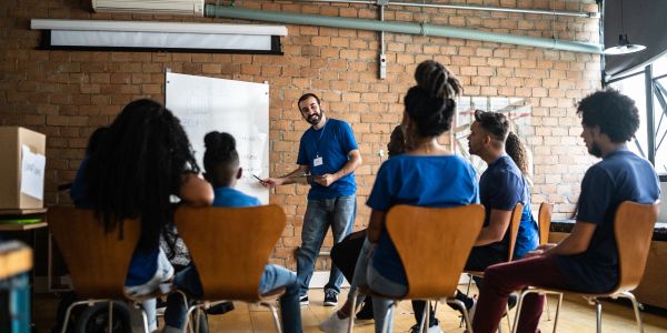 Man leading group discussion in casual meeting room.