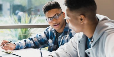 Two young men studying together and smiling.