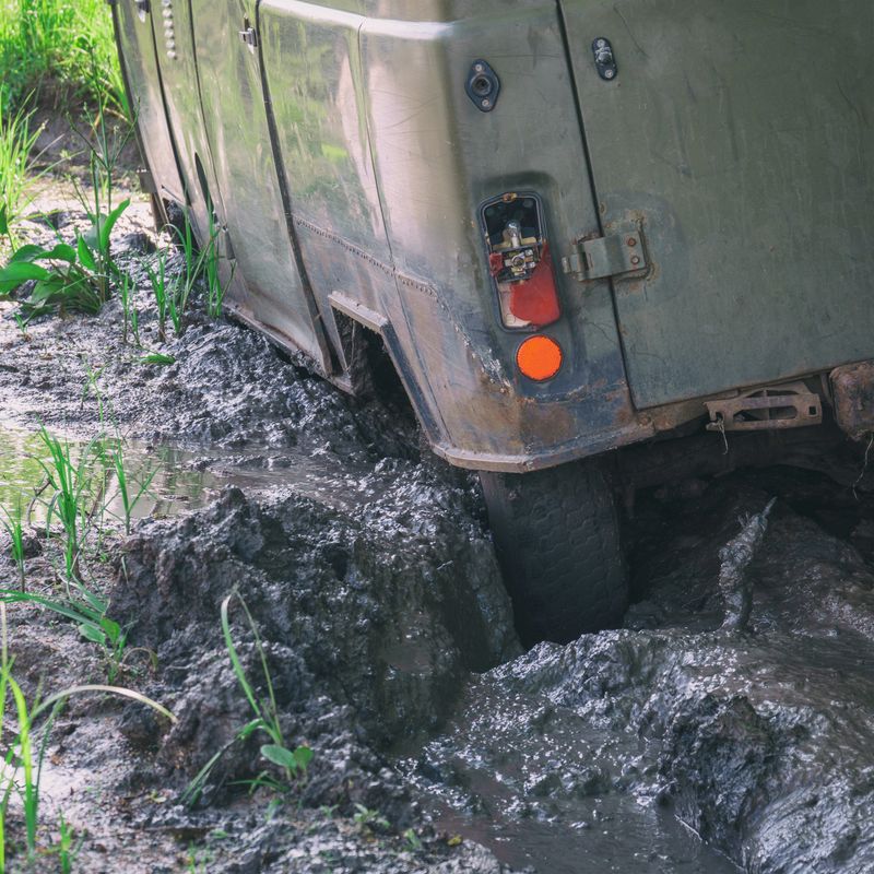 The wheel of an SUV stuck in deep mud on an impassable country road