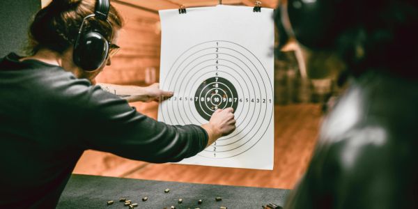 Person examining bullet holes on a shooting target.
