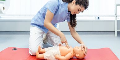 Person practicing CPR on infant doll.