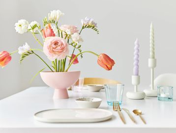Elegant table setting with pink flowers and pastel candles.