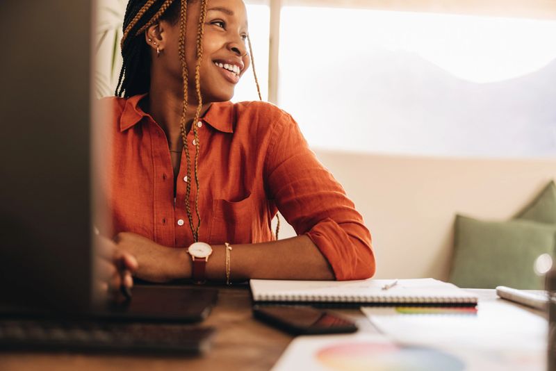 Female designer smiling while sitting in front of her computer. Happy young graphic designer drawing on a digital tablet with a stylus pen. Creative young woman working in her home office.