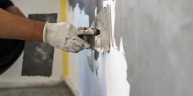 A person applying plaster to a wall with a trowel.