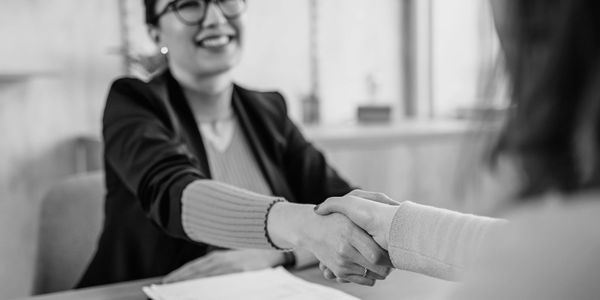 Two women shaking hands in a professional setting.