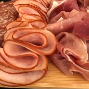 Close-up of assorted deli meats on a wooden board.