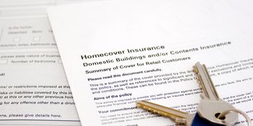 Close-up of a home insurance document with keys on top.