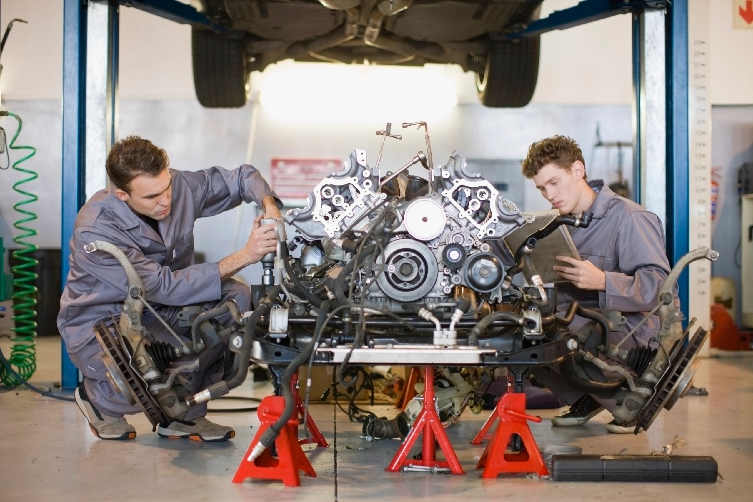 Two mechanics working on an engine in a workshop.