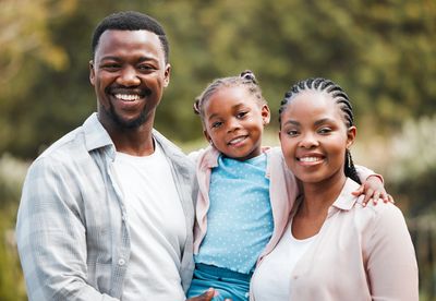 Smiling family outdoors representing health and life insurance coverage.
