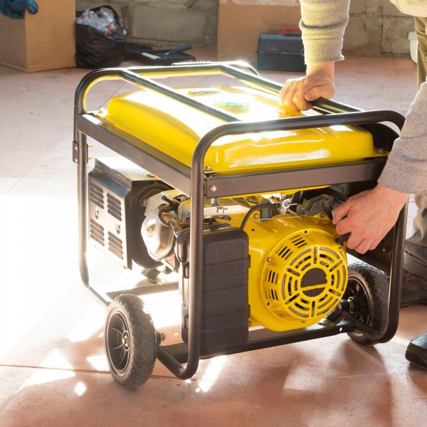 Person operating a yellow portable generator indoors.