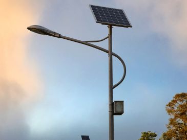 A solar-powered streetlight against a cloudy sky.
