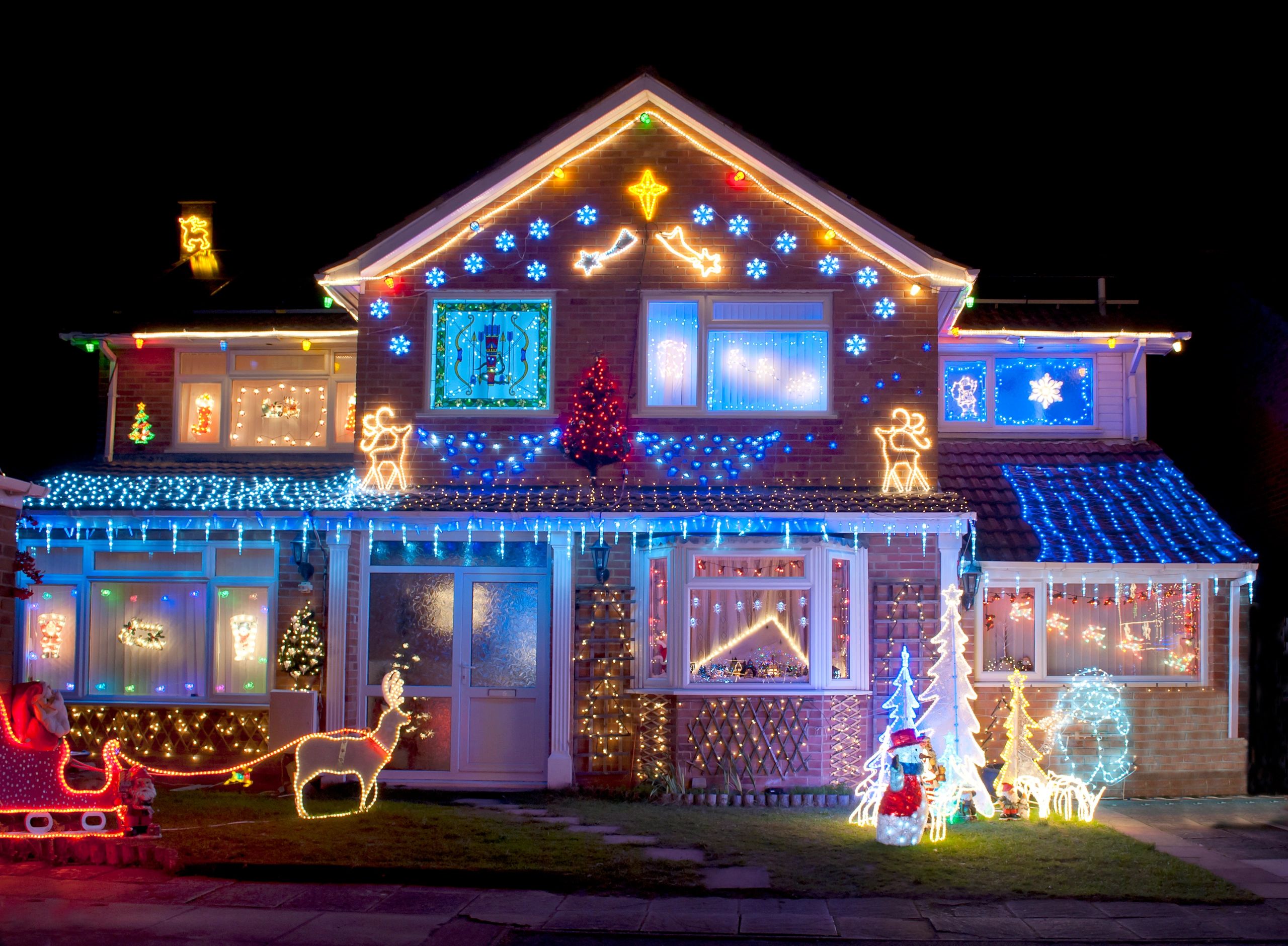 House decorated with colorful Christmas lights and festive figures at night.