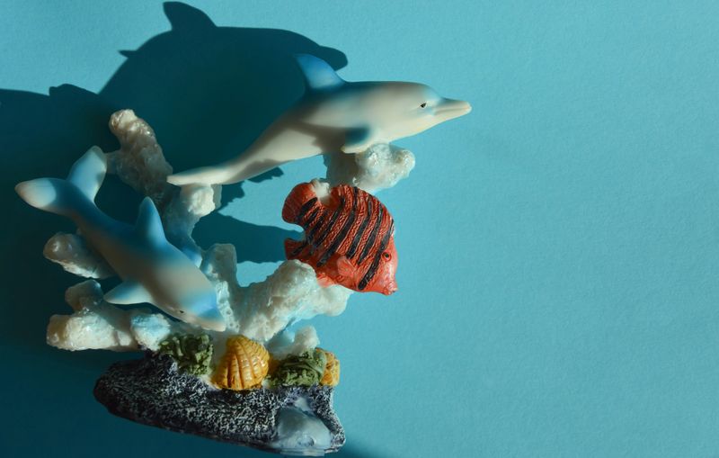 beautiful sea figurine of dolphins and fish on a blue background in the rays of the sun. preparing for the summer.