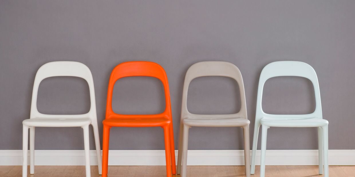 Four plastic chairs against a gray wall.
