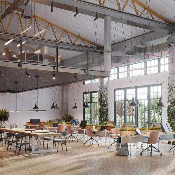 Modern open office space with desks, chairs, and large windows.