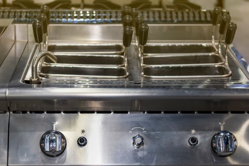 close up modern of gas deep fryer pot and knob dial control with metal stainless basket for industrial food