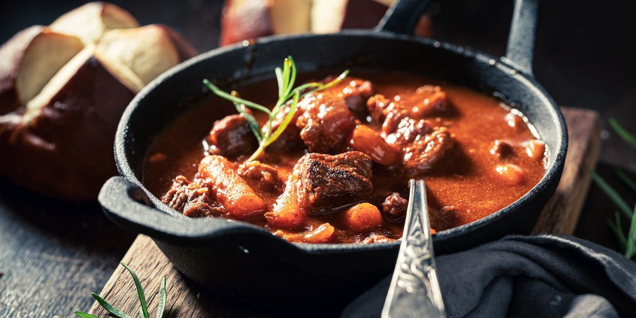 Hearty beef stew served in a cast iron pot with bread.