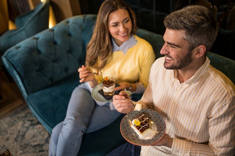 Beautiful couple eating delicious cakes together in a restaurant.