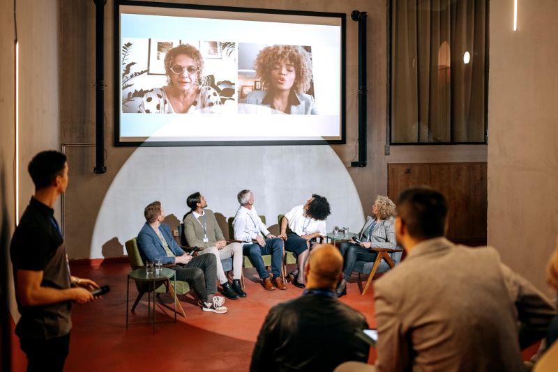 Group of presenters interacting with online presenters on a business presentation