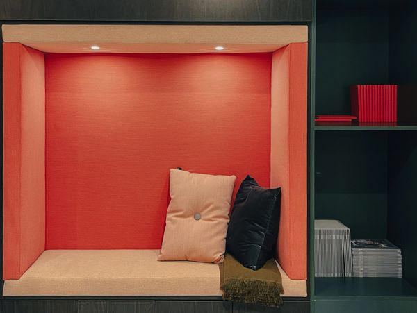 A cozy reading nook with cushions and soft lighting inside a modern shelving unit.