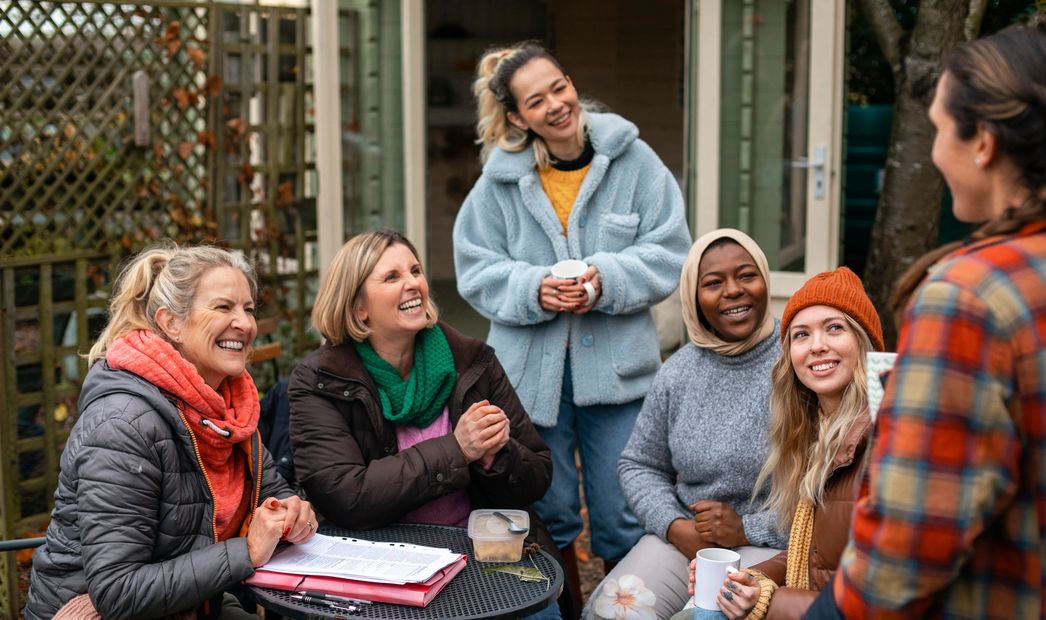 A group of diverse women enjoying a warm conversation outdoors.