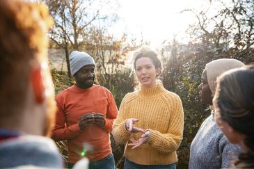 A diverse group engaged in a thoughtful outdoor conversation.