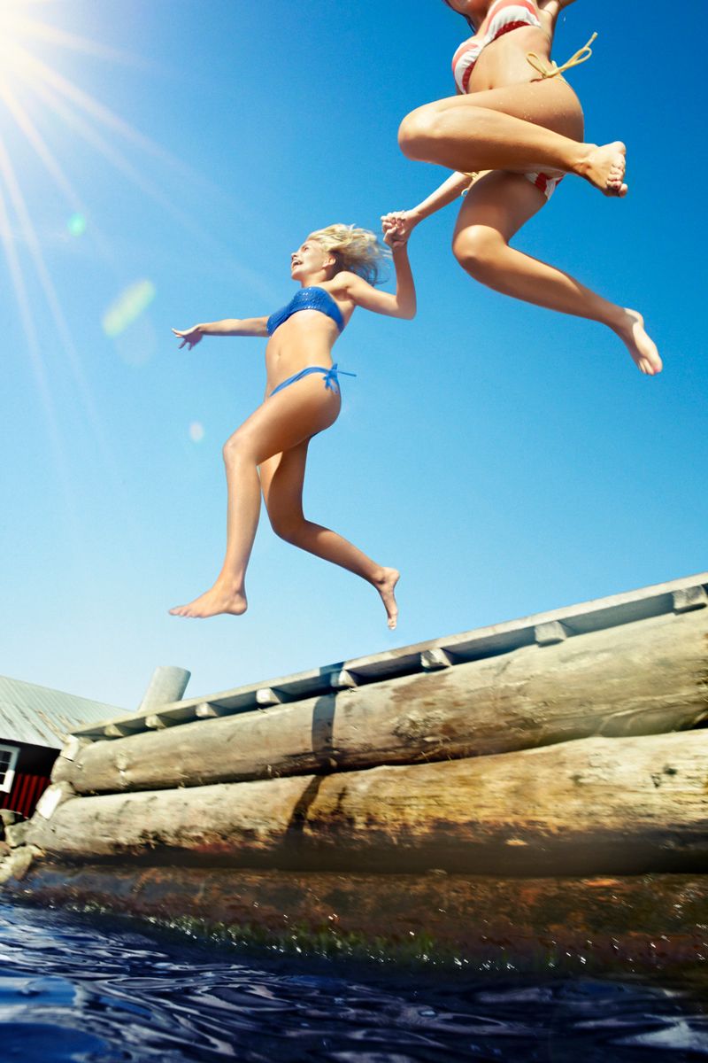 Teenage girls jumping into lake
