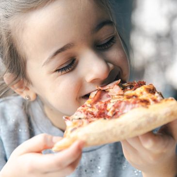 Young girl enjoying a slice of pizza.