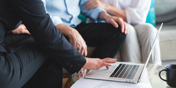 A professional shows a couple something on a laptop during a consultation.