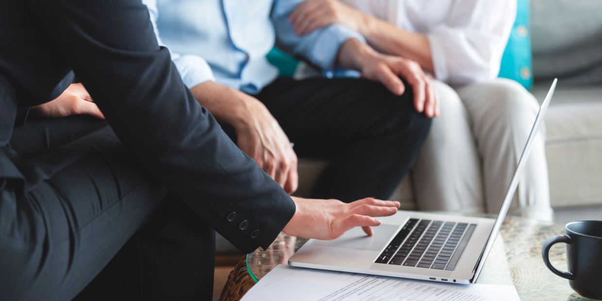 People engaged in a discussion around a laptop.
