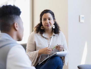 A woman attentively listens during a counseling session with a young man.