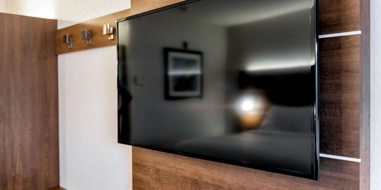 Flat-screen TV mounted on wooden panel in a room.