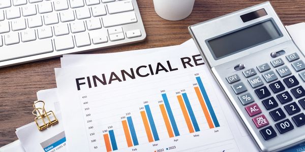 Financial report with bar charts, calculator, and keyboard on a wooden desk.