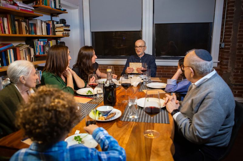 A modern Jewish American family celebrates Passover together.  The Seder leader holds up the middle matzo before breaking it.