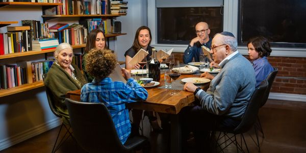 A family of seven enjoying a cozy dinner in a library-filled room.