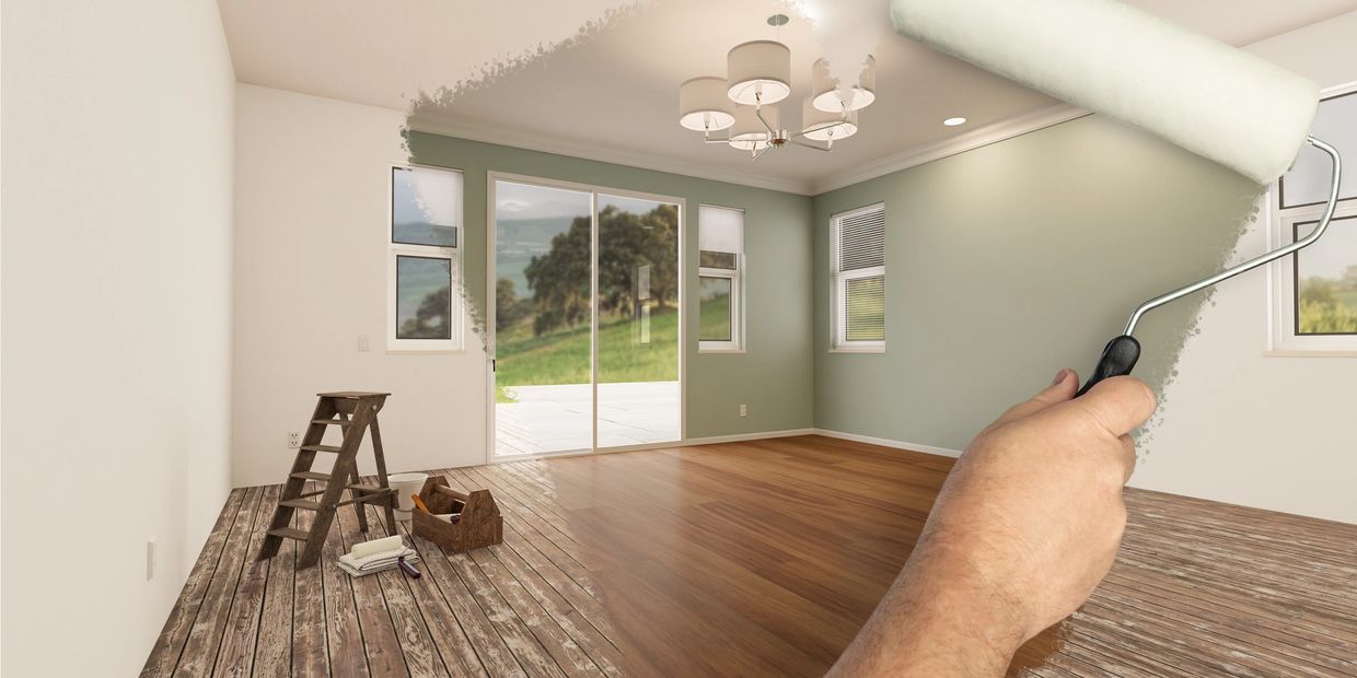 A hand painting a room wall with a roller, changing from green to white.