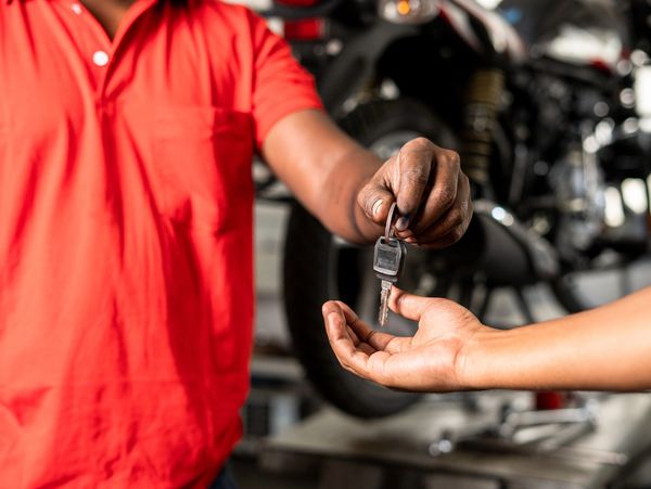 Person handing over a motorcycle key to another person.