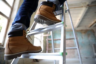 person climbing a ladder using 3 points of contact wearing safety boots 