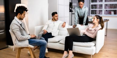 Four colleagues having a casual meeting in a modern office lounge area.