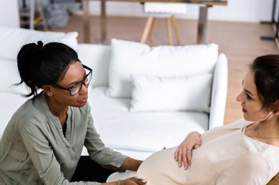 Pregnant woman receiving support from a doula at home.