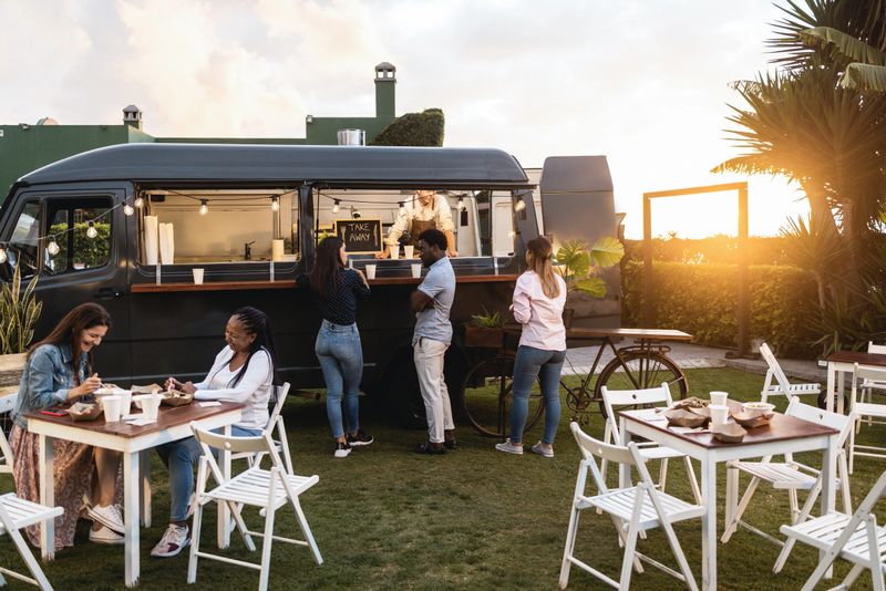 Multiracial people ordering gourmet food in front of take away restaurant truck outdoor - Main focus on african man face