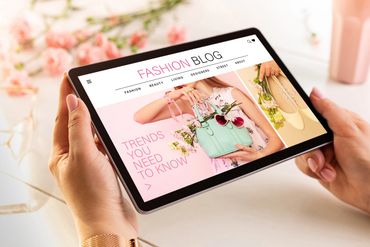 A person browsing a colorful fashion blog on a tablet featuring trends and accessories.