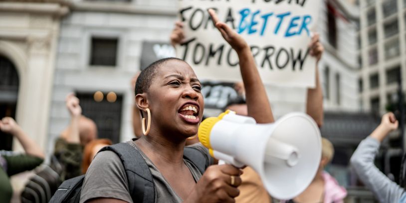 Woman passionately speaking into a megaphone during a protest.
