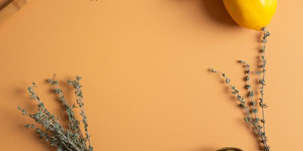 Dried herbs and a yellow bell pepper on a warm orange background.