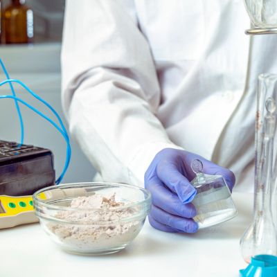 Scientist handling chemical sample with gloved hand in lab.