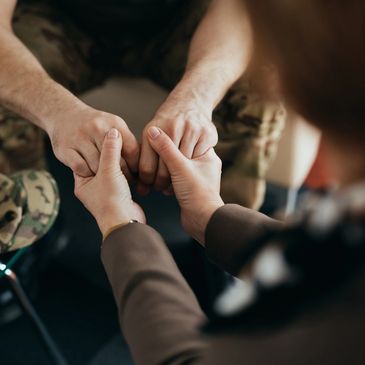 A person comforting a soldier by holding their hands.