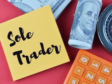 Sticky note with 'Sole Trader' text surrounded by money and calculator.