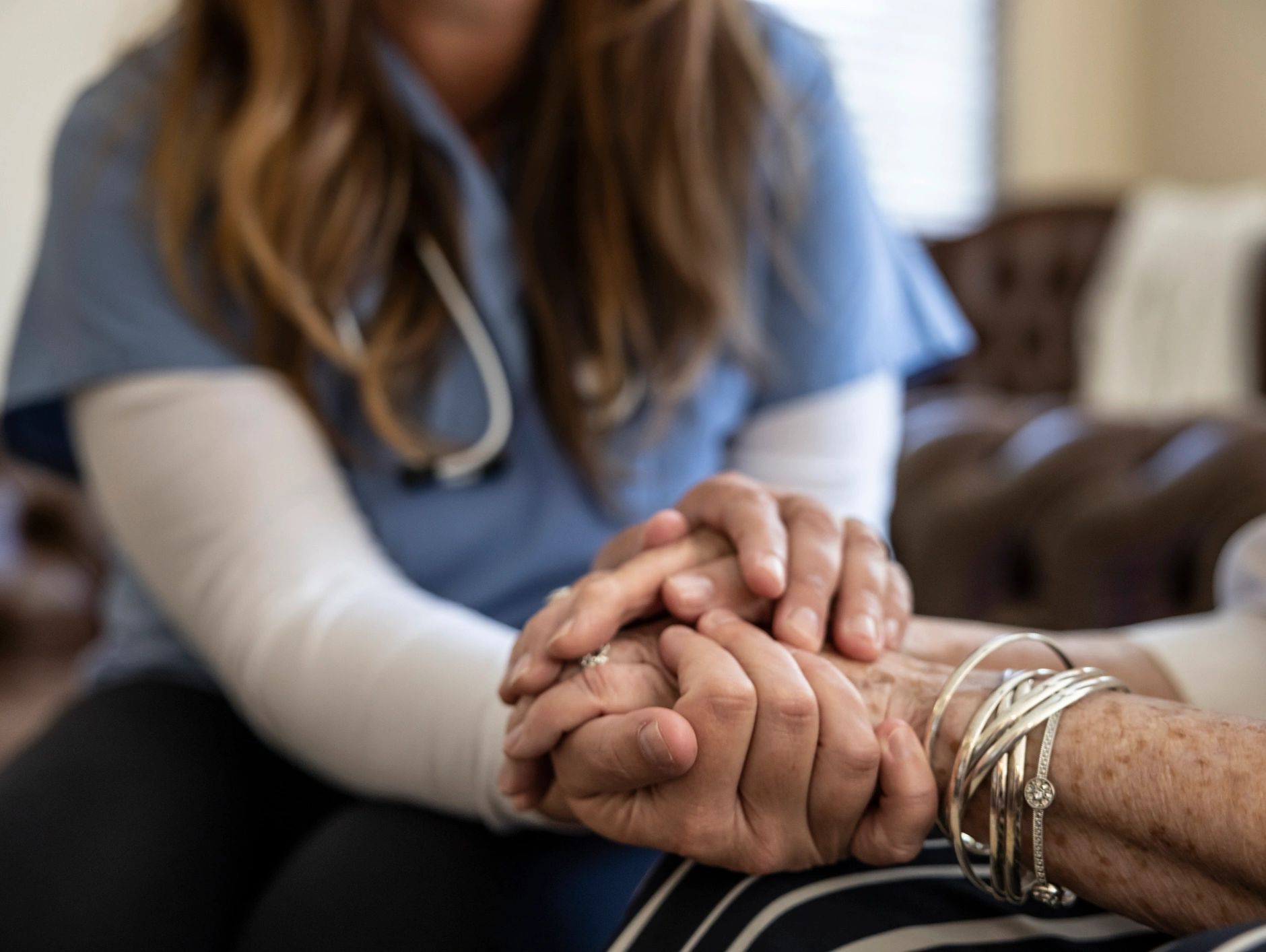 Healthcare worker holding elderly patient's hand with kindness.